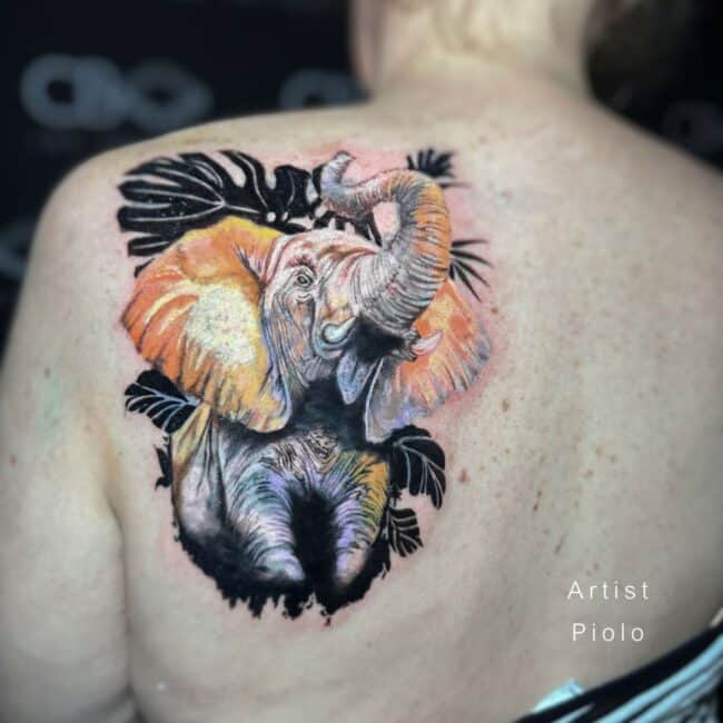 Piolo Tattoo Artist Realism Colour Elephant Roaring Colour Orange Ears Palm Leaves in the Background Back Shoulder Tattoo