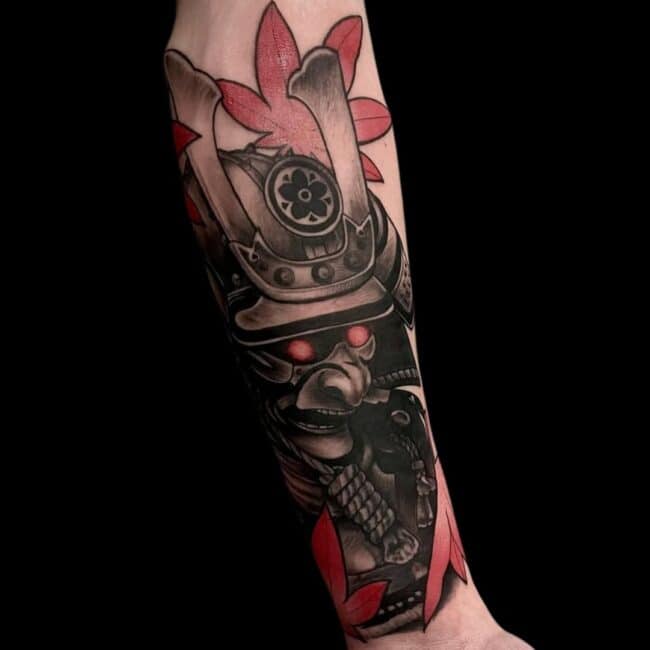 Rhys Tattoo Artist Japanese Black and Grey Colour Detailed Samurai Mask Red Eyes Red Leaves In The Background Forearm Tattoo
