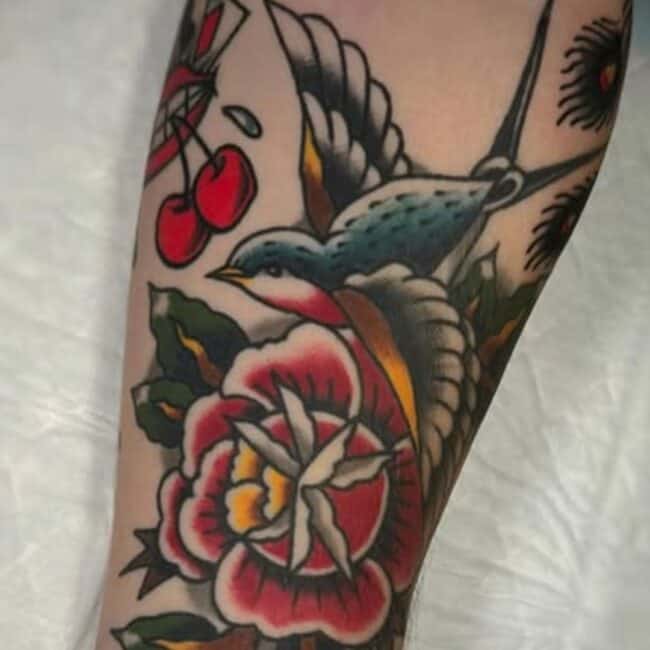 Traditional Colour Swallow Bird Vibrant Flower Lush Green Leaves Forearm Tattoo