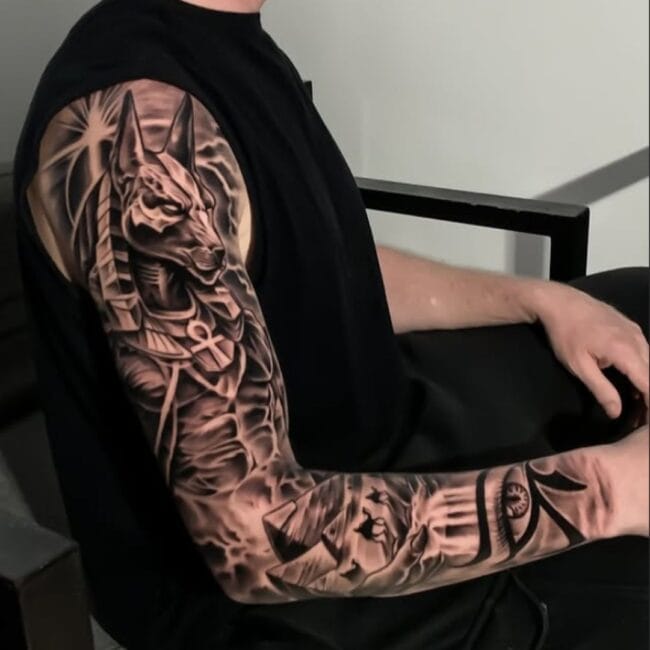 Black and Grey Realism Blackwork Anubis Jackals Head Eye of Horus Ancient Egyptian Symbol Bold Ankh Shaped Cross with Loop Scarab Beetle Pyramid Desert Hand Sleeve Arm Tattoo
