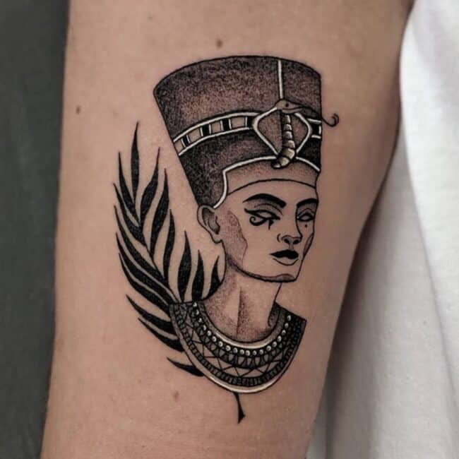 Black and Grey Realism Fineline Geometric Nefertiti Portrait Ancient Egyptian Symbol Detailed Eye of Horus Nose Lips Crown Ancient Ornate Collar Leaves Behind Forearm Tattoo
