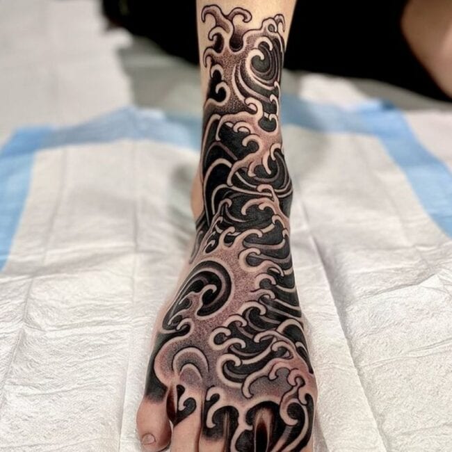 Black and Grey Blackwork Mandala Japanese Wave Pattern Sweeping Curves Bold Spirals Deep Blacks Ankle Foot Tattoo